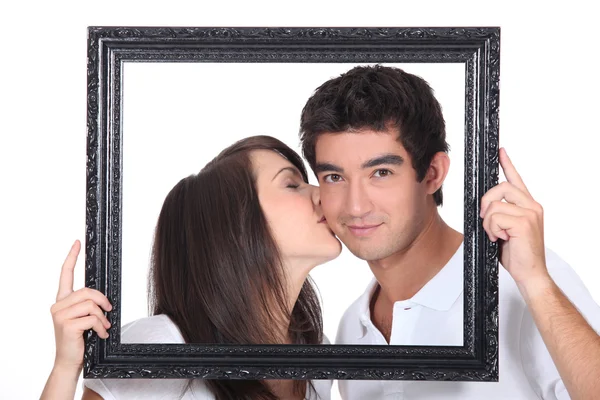 Menina ternamente beijando um homem na bochecha atrás de quadro preto — Fotografia de Stock