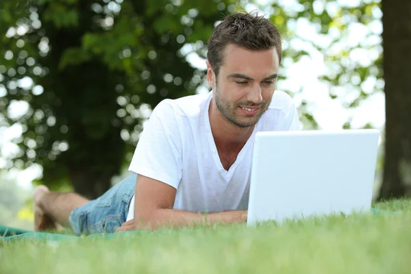 Uomo posato in campo con computer portatile — Foto Stock