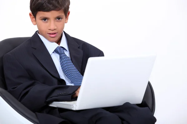年轻的男孩穿着成人商务套装用一台笔记本电脑 — 图库照片