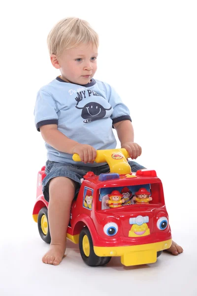 Petit garçon assis sur une voiture jouet — Photo