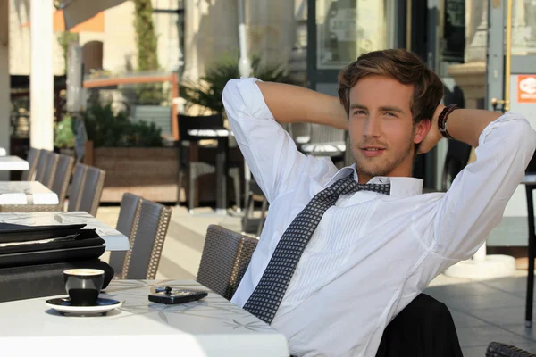 年轻男子穿西服打领带，在早餐时间的露台上放松 — 图库照片