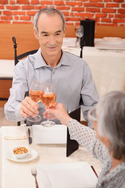 Старшая пара пьет розу в ресторане — стоковое фото