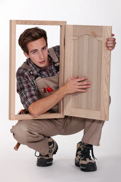 Um jovem carpinteiro mostrando uma peça de mobiliário — Fotografia de Stock