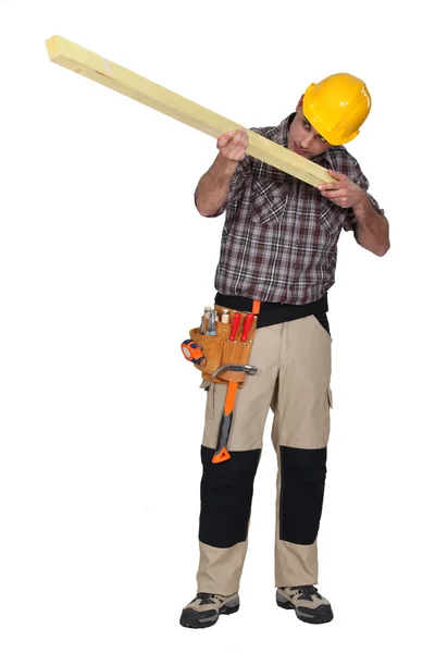 Builder eyeing a plank of wood — Stock Photo, Image