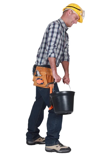 Um pedreiro carregando um balde . — Fotografia de Stock