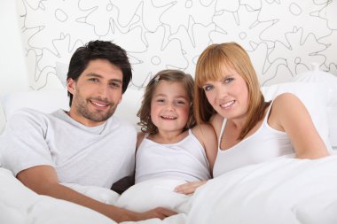 Family in bed together on Sunday morning clipart