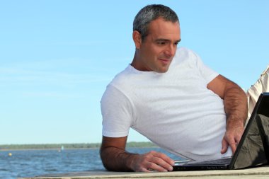 Mature man with laptop outside clipart