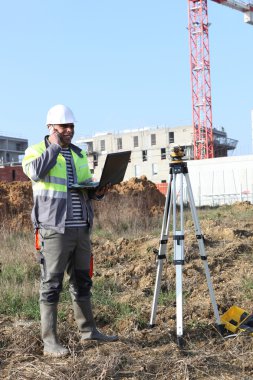 Surveyor on site with a laptop clipart