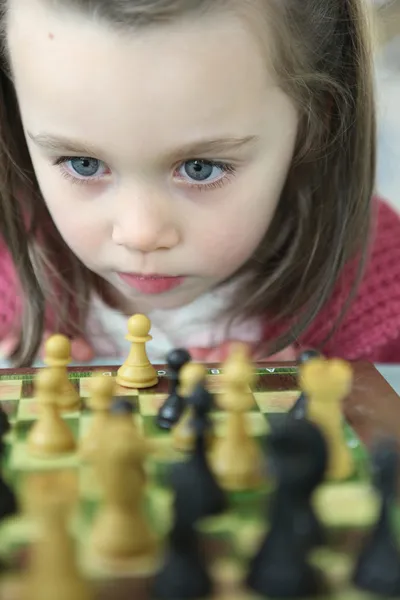 Маленькая девочка играет в шахматы — стоковое фото