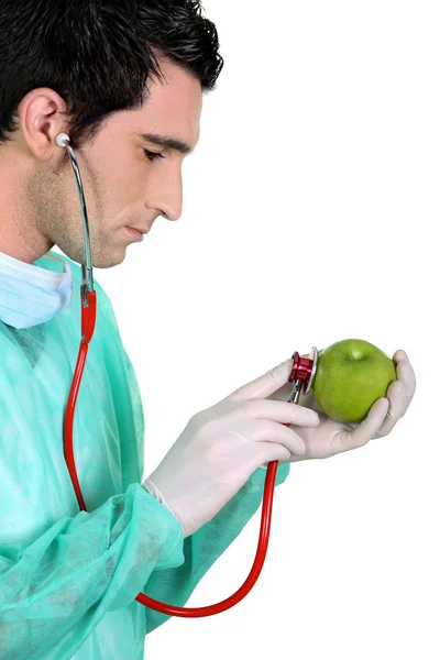Médico examinando uma maçã com um estetoscópio — Fotografia de Stock