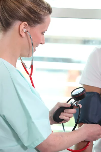 Egy nővér, figyelembe véve a vérnyomás egy beteg — Stock Fotó