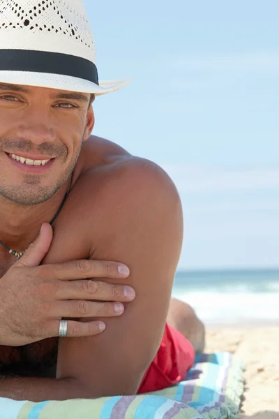 男子戴着帽子在海滩日光浴 — 图库照片