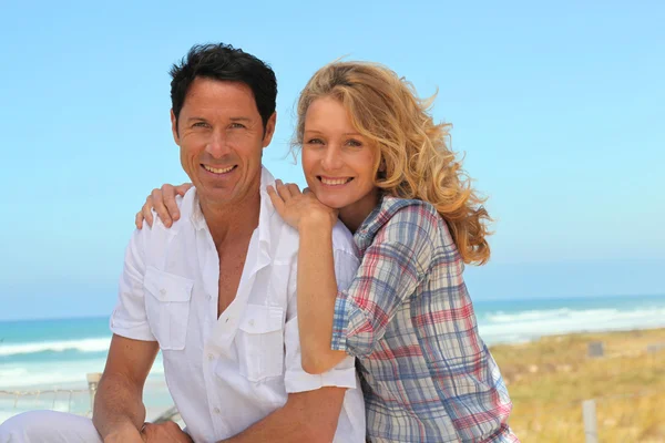 Lyckliga par avkopplande på stranden — Stockfoto