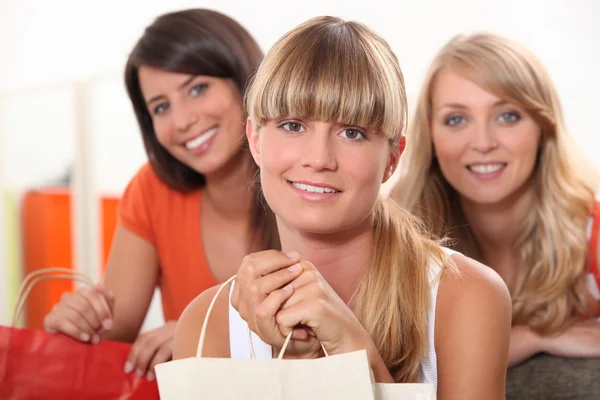 Drie vrouwelijke vrienden thuis met shopping tassen — Stockfoto