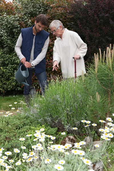 Senior med trädgårdsmästare vattna växter — Stockfoto