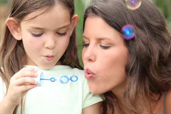 Madre e hija soplando burbujas — Foto de Stock