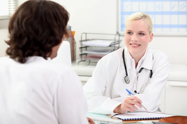 Usmívající se žena doktor mluvit mužský pacient — Stock fotografie