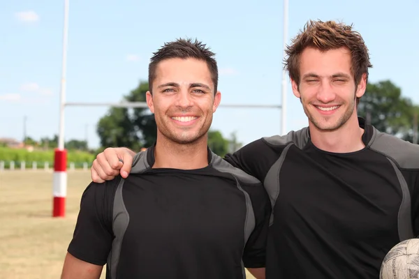 Deux joueurs de rugby posant avec une balle devant le but — Photo