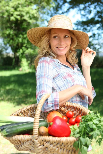 Mulher com um chapéu de palha e cesta de legumes . — Fotografia de Stock