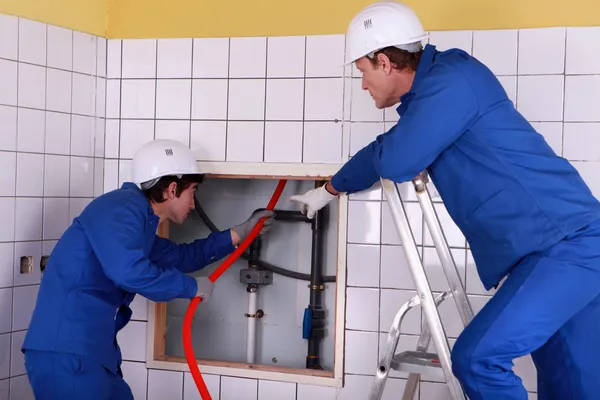 Два водопроводчика работают в общественном туалете — стоковое фото