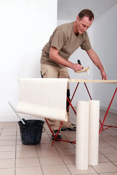 Man putting glue on wallpaper — Stock Photo, Image
