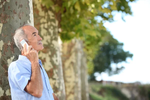 Παλαιότερη άνθρωπος σε εξωτερικούς χώρους με ένα κινητό τηλέφωνο — Φωτογραφία Αρχείου