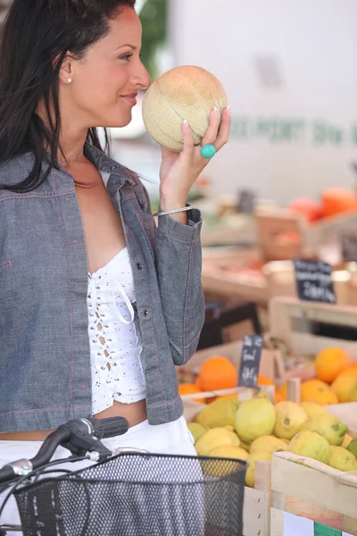 Mulher cheirando um melão no mercado — Fotografia de Stock