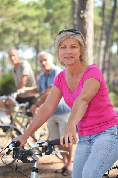 Mujer montando en bicicleta con amigos en un bosque — Foto de Stock