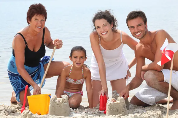 Famiglia costruzione castelli di sabbia sulla spiaggia — Foto Stock