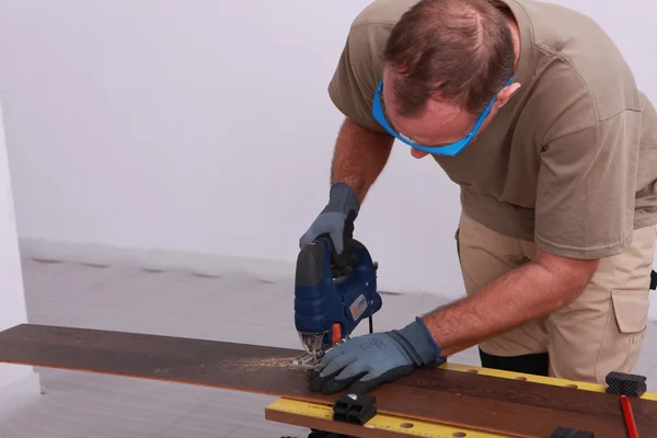 Hombre cortando una tabla del suelo — Foto de Stock