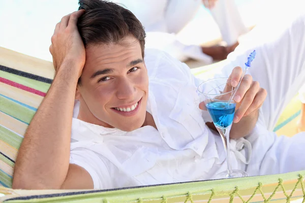 Giovane uomo che si gode un cocktail su un'amaca — Foto Stock