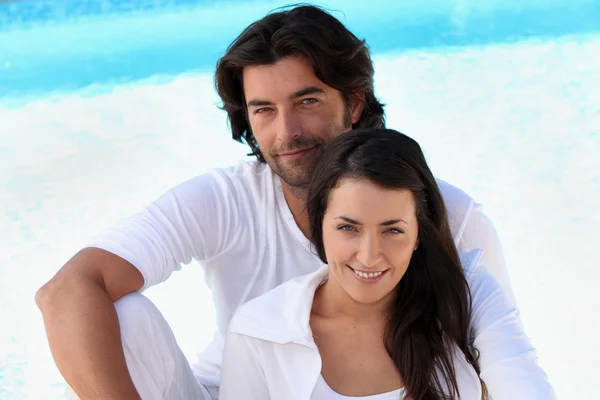 Kärleksfull unga paret sitter av en pool — Stockfoto