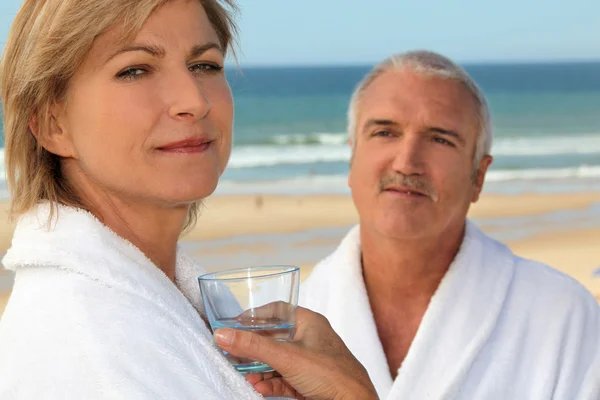 Gift par på stranden bär badrockar — Stockfoto