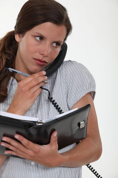 Sekreterare prata i telefon och titta på hennes agenda — Stockfoto