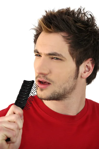 Jovem segurando escova de cabelo como microfone improvisado — Fotografia de Stock