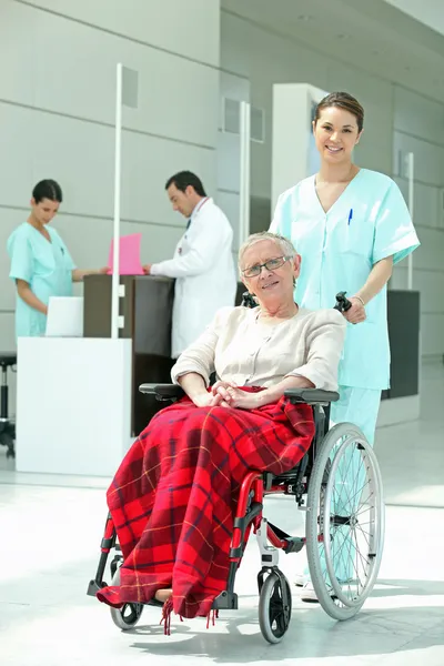 Infirmière poussant une femme âgée dans un fauteuil roulant — Photo