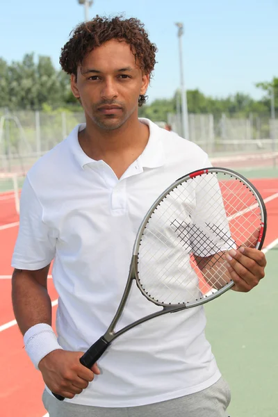 Ein Tennisspieler hält seinen Schläger in der Hand und schaut uns an. — Stockfoto