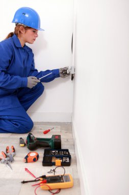 Female electrician installing a wall socket clipart