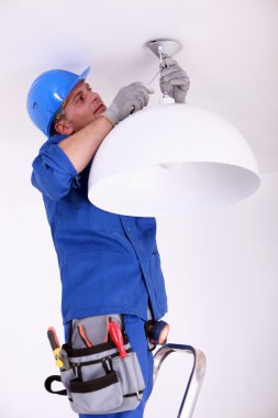 Electrician fitting a ceiling light clipart