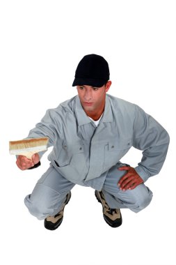 Craftsman painter kneeling and holding a brush clipart