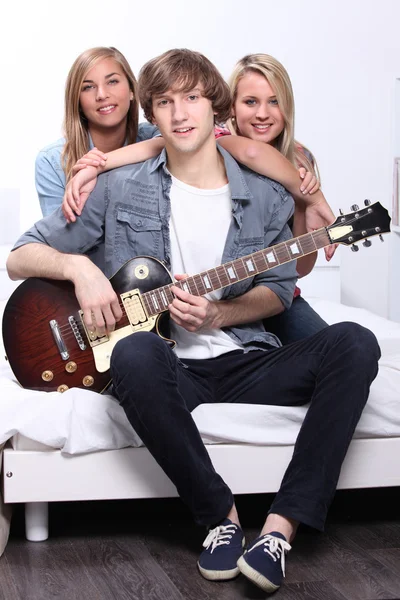Tieners spelen een gitaar in een witte slaapkamer — Stockfoto