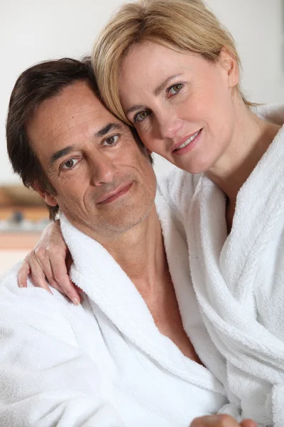 Kvinna iklädd morgonrock vit toweling sitter i hennes partner knä — Stockfoto