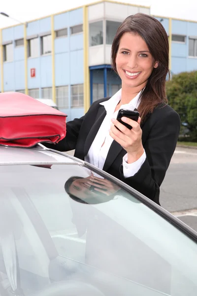 A telefon mellett a kocsiját mosolyogva üzletasszony — Stock Fotó