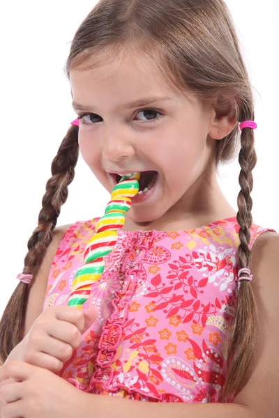 Маленька дівчинка з вішаками смокче льодяник — стокове фото