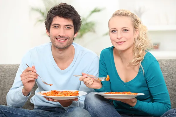 Couple having dinner on the couch — Stock Photo, Image