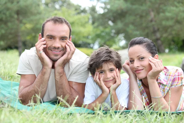 Familia feliz tendida en la hierba — Foto de Stock