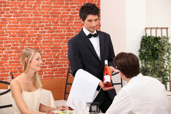 Casal jovem escolhendo vinho rosa em um restaurante — Fotografia de Stock