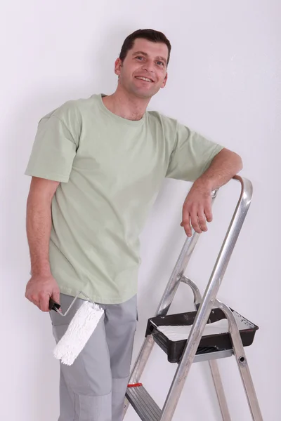 Man using a roller to paint a room white — Stock Photo, Image