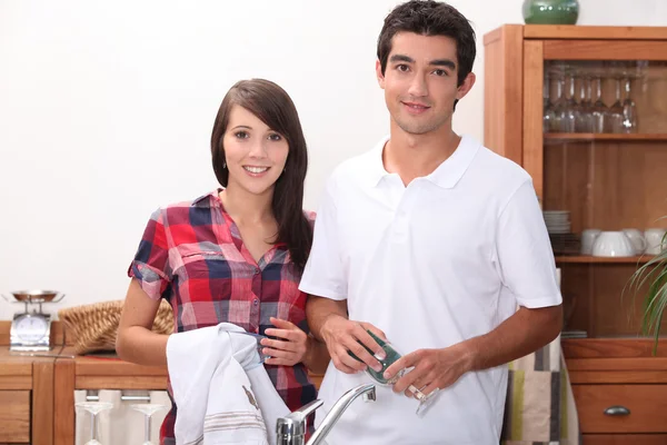 Молодая пара вытирает очки на кухне — стоковое фото
