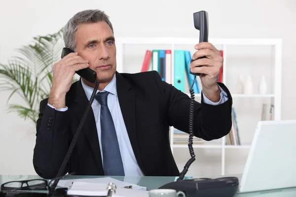 Empresario en dos llamadas telefónicas — Foto de Stock
